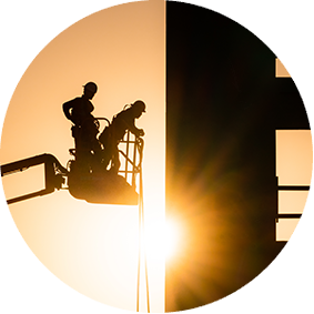 two construction workers on a high-lift with the sun rising in the background
